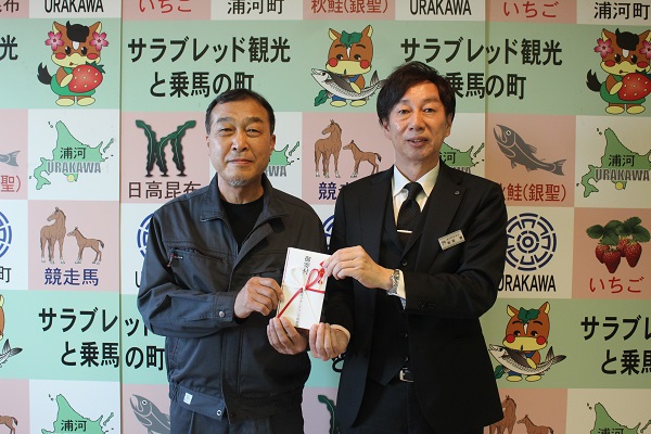 浦河フォークソング倶楽部（吉田弘幸代表）より和田教育長へ寄附金を手渡す様子